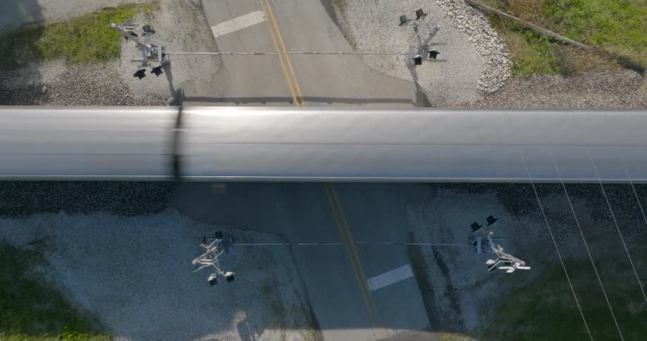 Descending towards a passenger train speeding past a road crossing