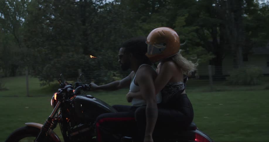 Man riding a motorcycle with a woman wearing a helmet holding on to him