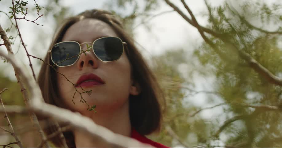 A young woman stands by a tree in the forest and looks around