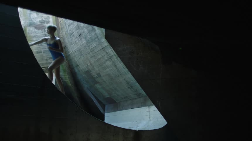 A dancer tries to walk up a slanted cement wall