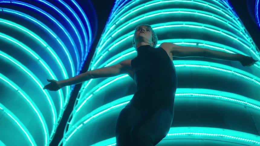 A woman dances in front of colorful buildings downtown