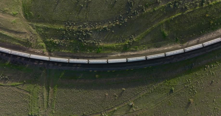 Top down view of train cars casting long shadows on a green landscape
