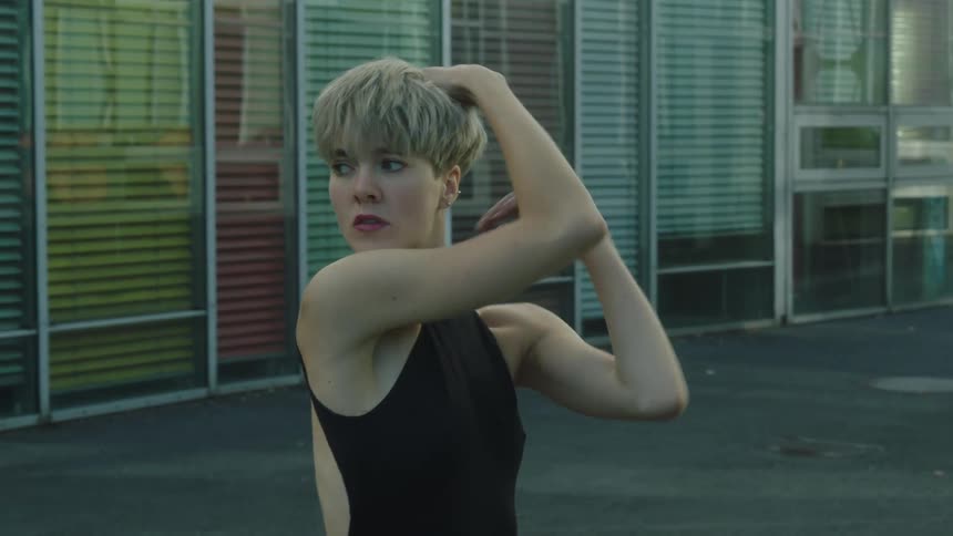 A woman dances in front of a building