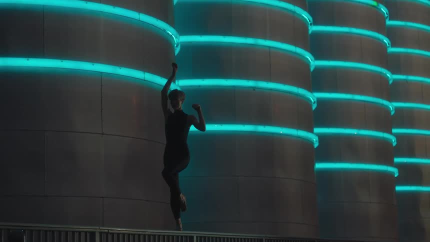 A silhouetted woman doing dance poses while balancing on a rail