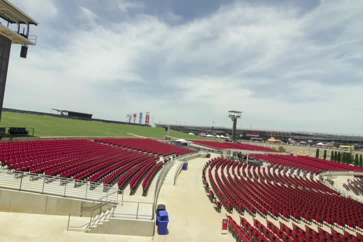 People walk around near some seats by an outside stage