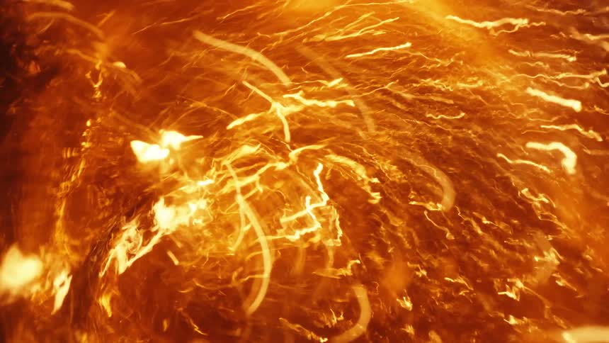 Chaotic light streaks and patches in yellow vibrate and shake against a darker orange background