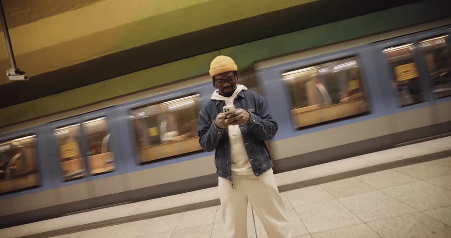 A man using a smartphone while standing on a subway station platform