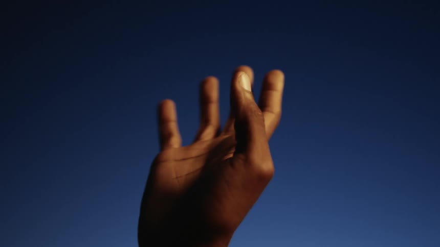 Persons hand is silhouetted against the night sky before it comes into the light