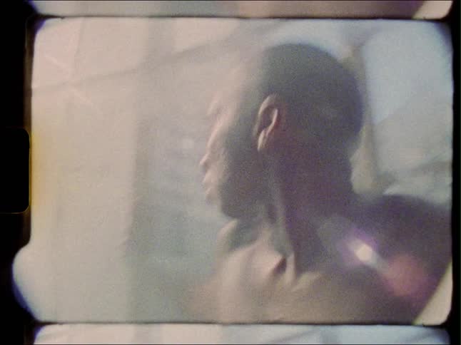 A man moving abruptly around against tall windows