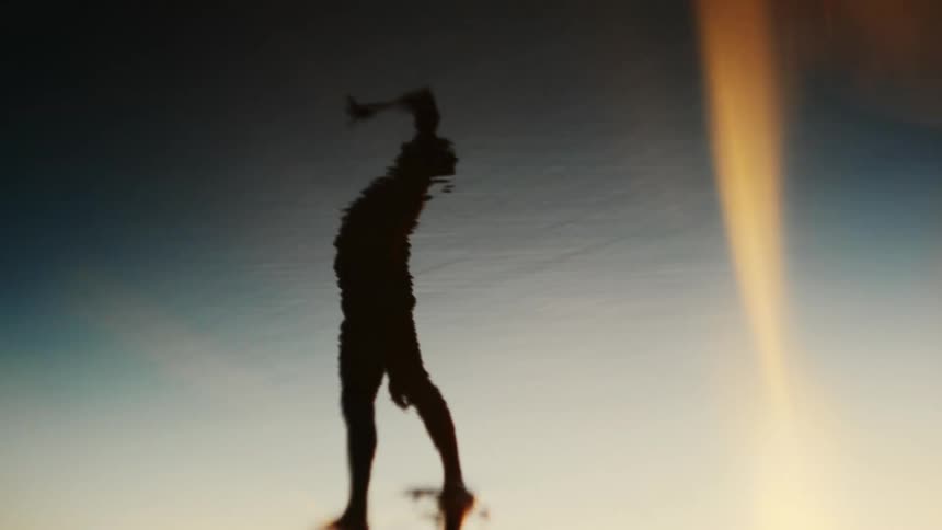 A man leans down and waves his arms up and down while dancing