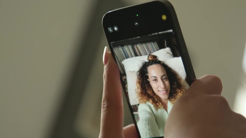 A woman takes a selfie with her phone while lying down