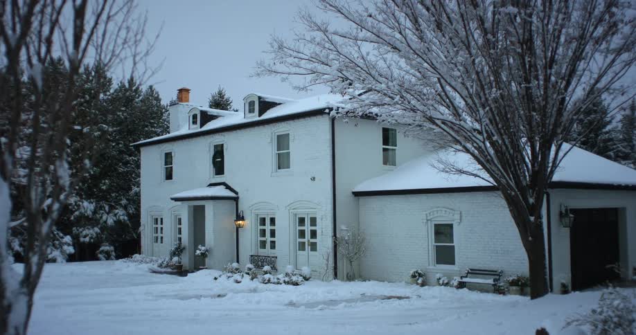 Heavy snow covers the roof and front yard of a suburban home