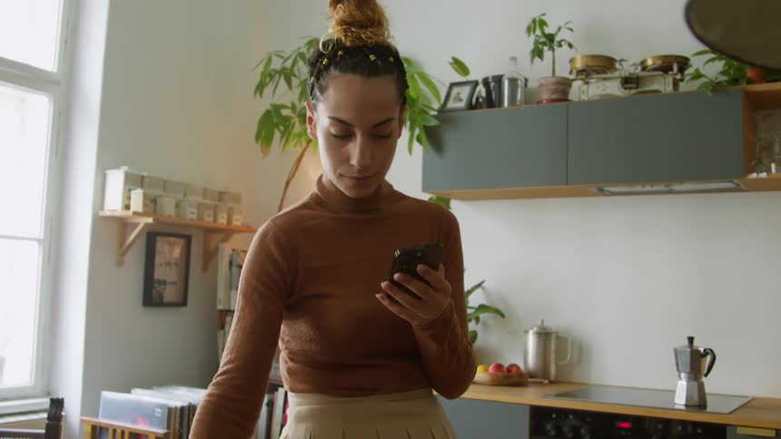 Woman sips from coffee mug then texts on cell phone