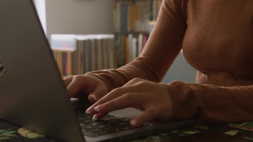 A woman types on her laptop at home