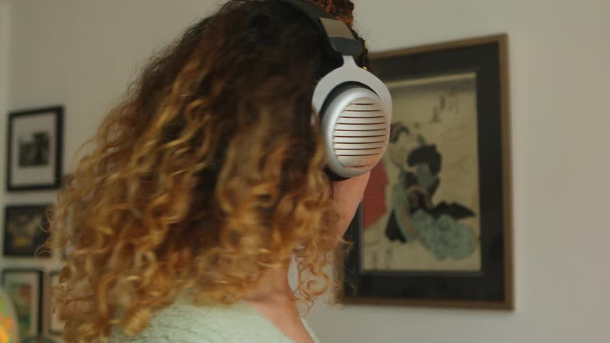 A woman putting on headphones next to a record player at home