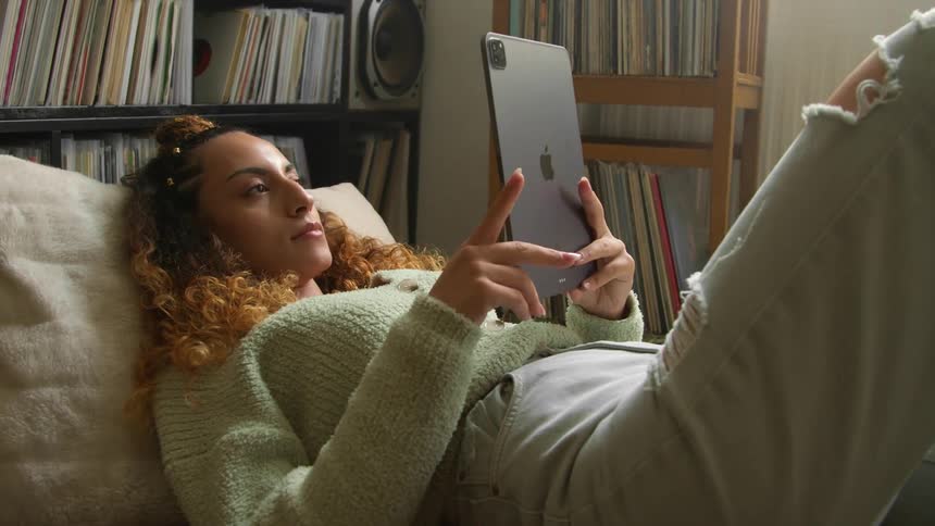 A woman using a tablet while laying around