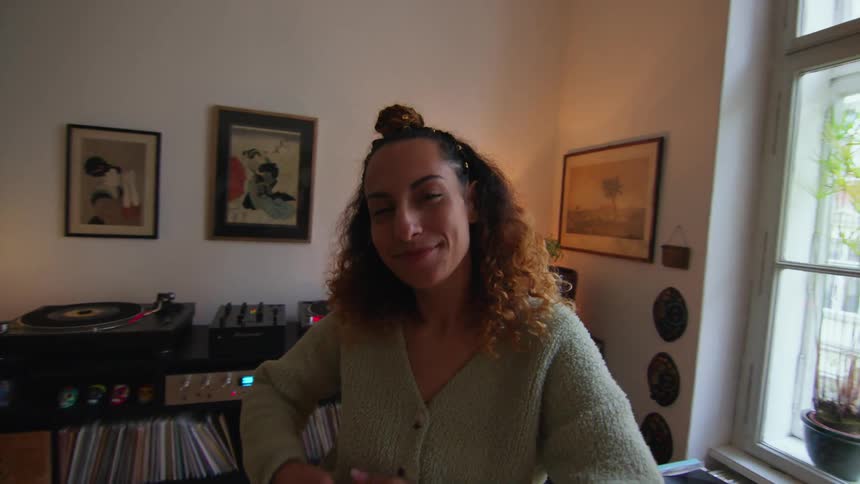 A woman dancing in her living room with her hands swaying and moving about