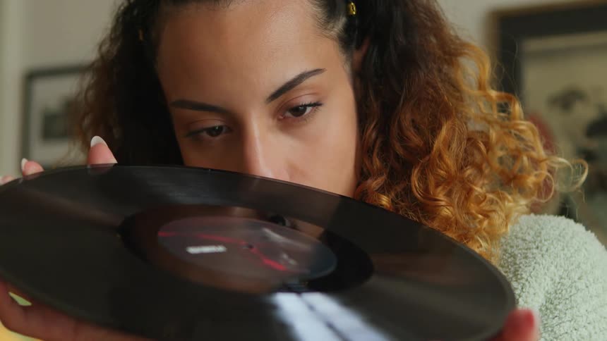 Woman with curly hair closely examines vinyl record