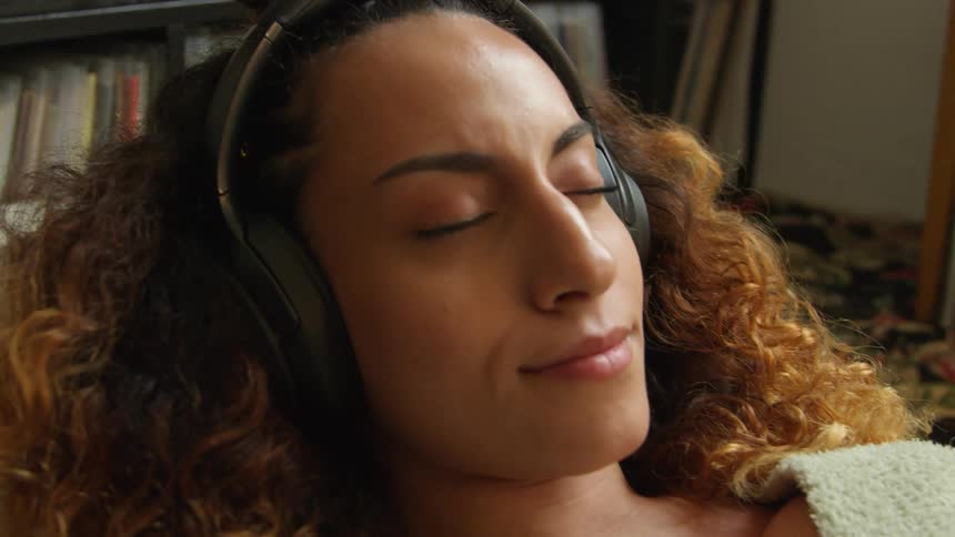 A woman listens to music while lying down