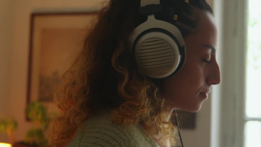 A woman is smiling and listening to music on headphones