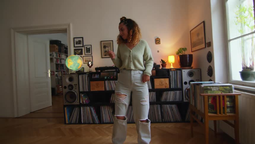 A woman dances while listening to music on a record player