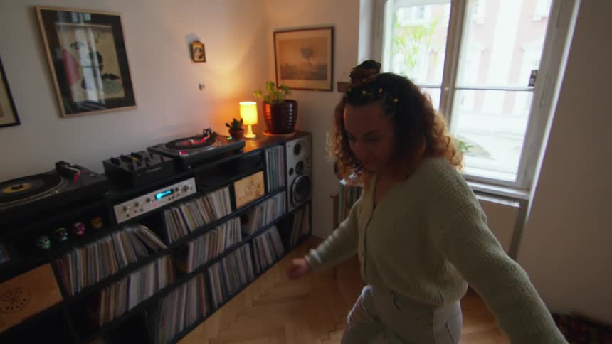 A woman dancing while listening to a record player in a living room
