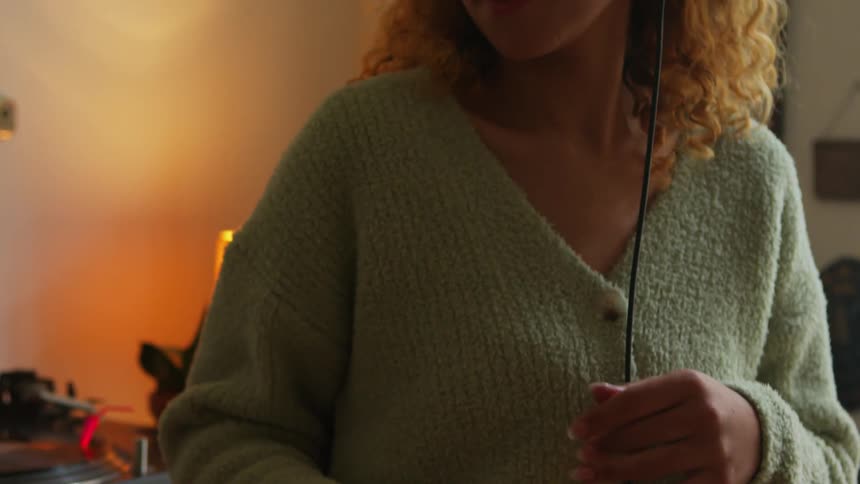 A woman wearing a green sweater dancing listening to music in headphones