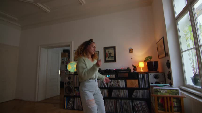 A woman dances while listening to music in her living room