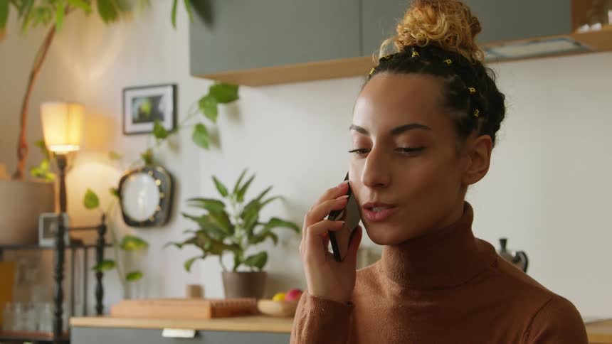 A woman is smiling as she talks on her phone