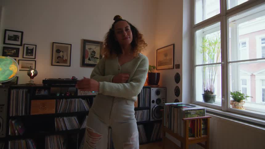 A woman dances while listening to music in her living room