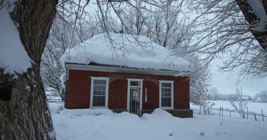 Snow falls on a small home in a rural area