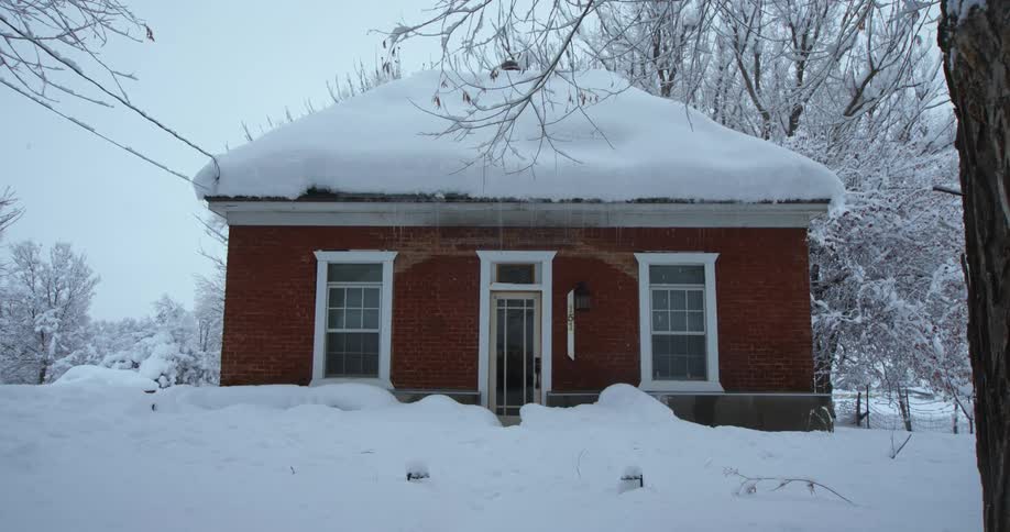 Heavy snow covers the roof on a home and the surrounding trees