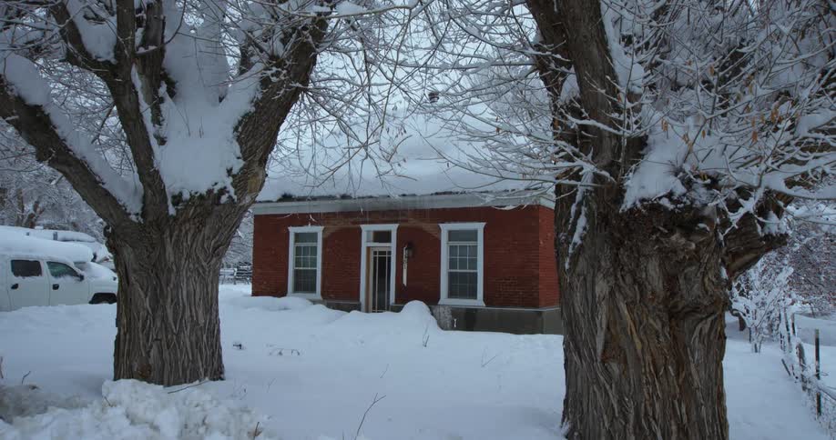 A dusting of snow falls over a home already covered with a thick layer
