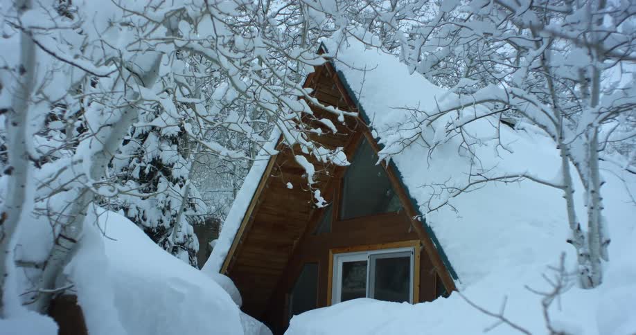 Snow covers roof and area around cabin thickly