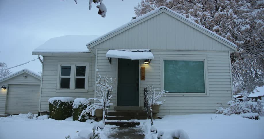 A small white house surrounded by snow in winter