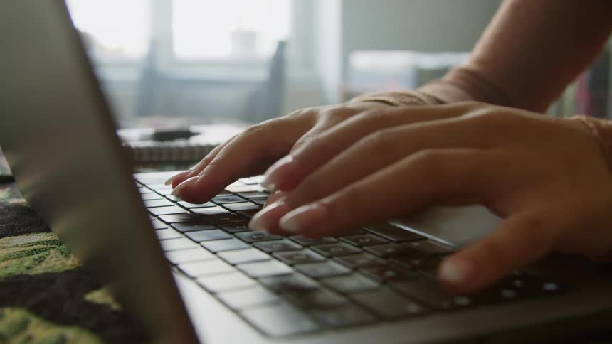 A woman types on her laptop at her desk