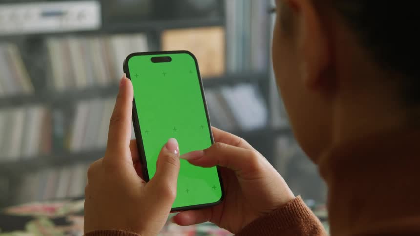 Woman texts on smartphone in room with shelves full of albums