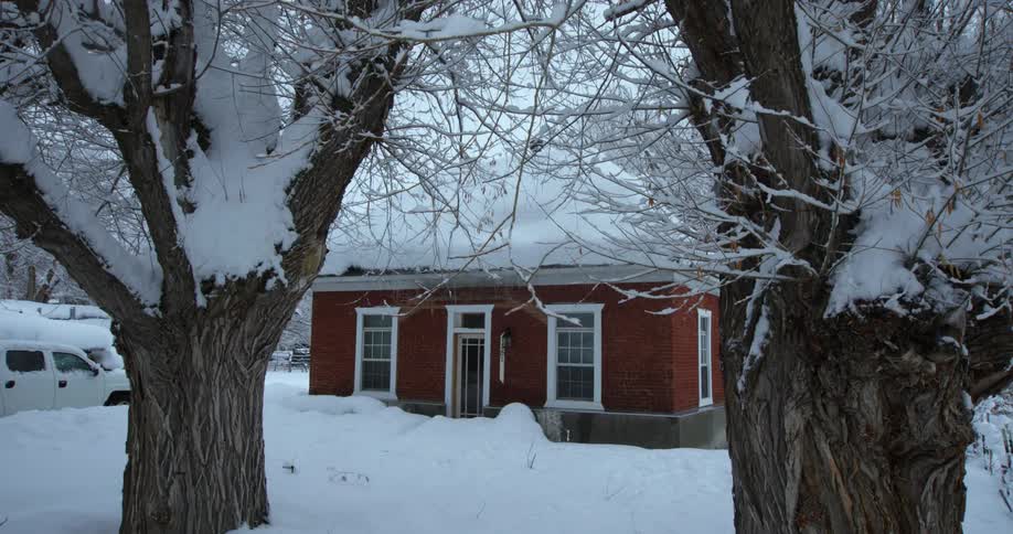 Heavy snow covers the ground and trees surrounding a small home