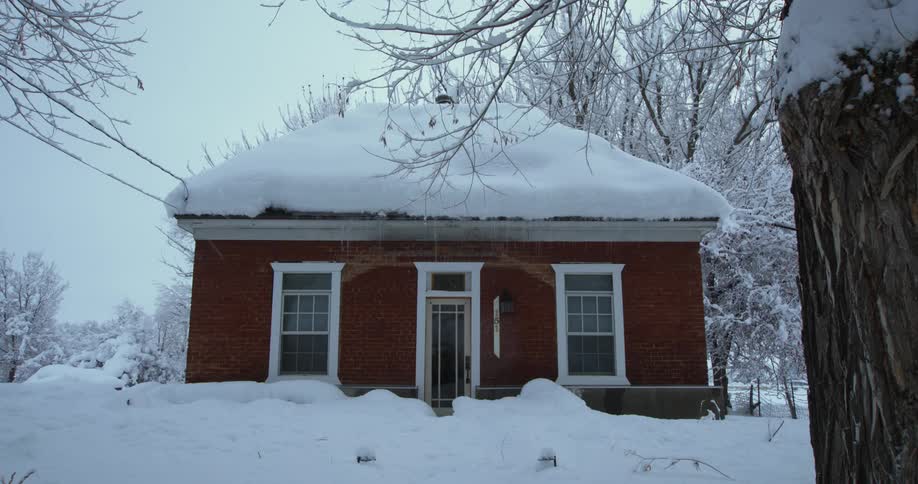 Heavy snow has fallen on a small home near snow covered trees on a winter day