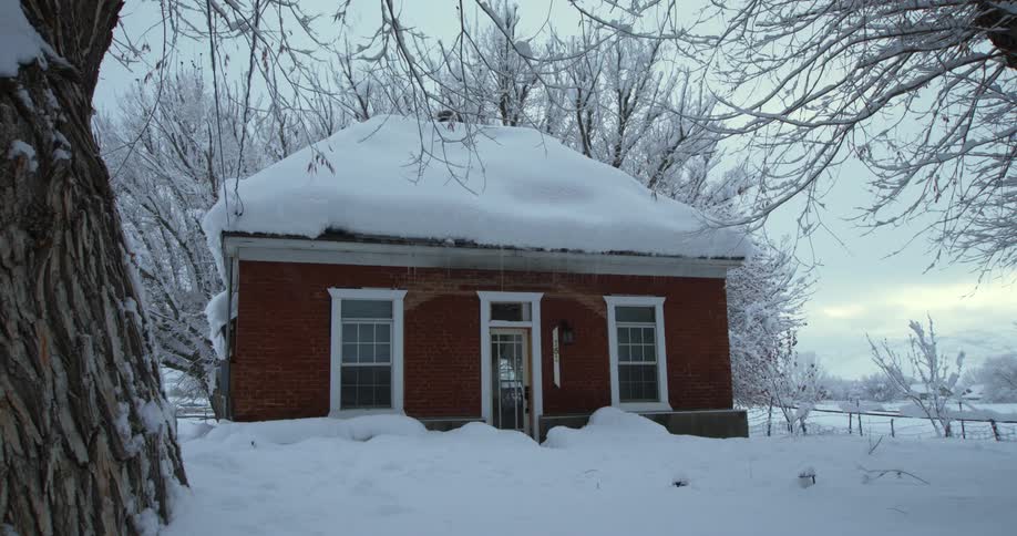 Heavy snow has fallen on a small rural home near snow covered trees on a winter day