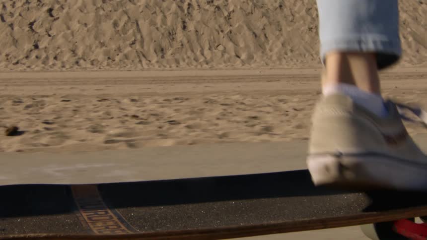 A woman runs alongside her skateboard before jumping on