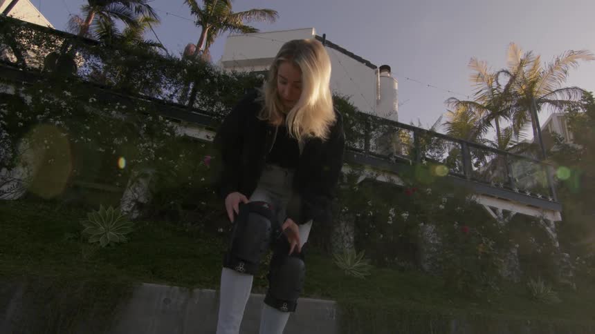 A blonde woman bent over putting on knee pads