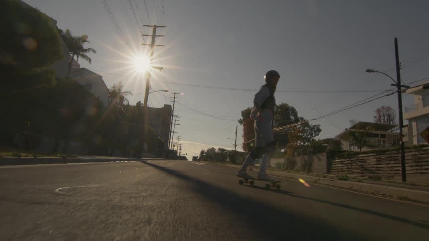 A woman is skateboarding on a street in a neighborhood