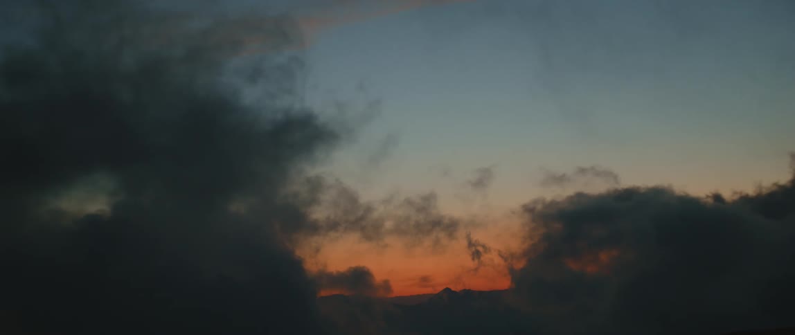 An orange and blue sky horizon at dusk with clouds rolling in