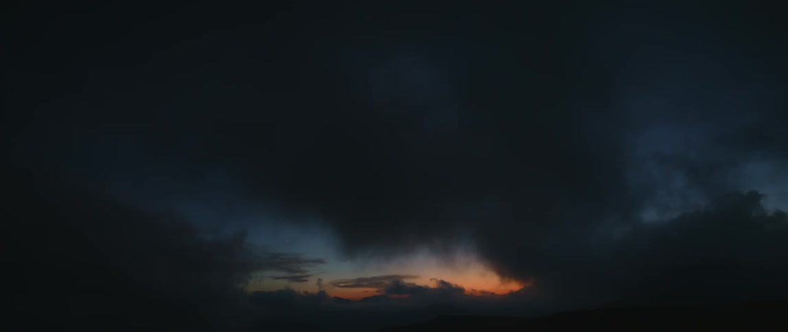 A horizon with the sun setting and clouds overhead