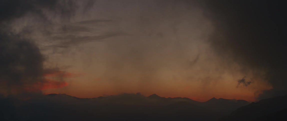 Heavy smoke fills the sky over a mountain range