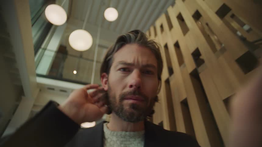 Man with beard and black blazer jacket with brown sweater uses tablet in the office