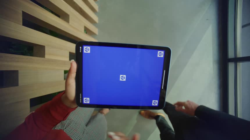 Man and woman stand in office discussing contents of a tablet