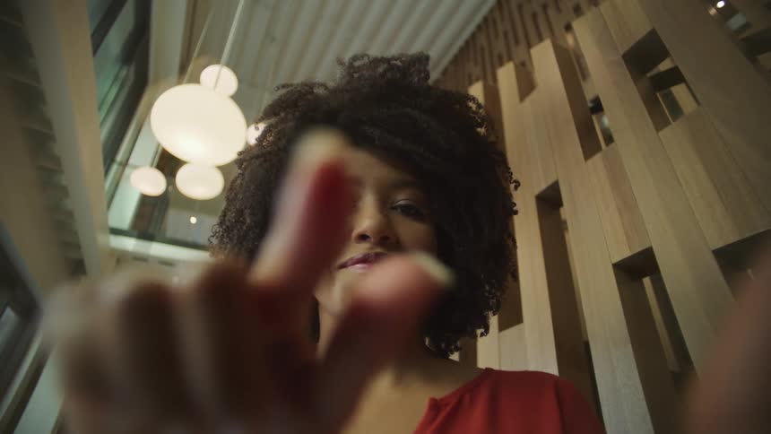Businesswoman with curly hair and red blouse uses tablet in the office building