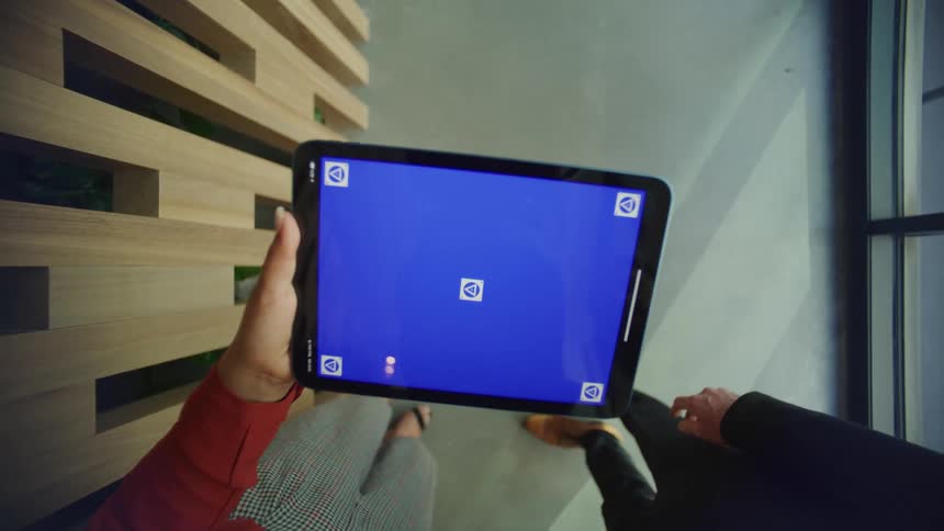 A man and woman talking over a tablet in an office setting